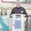 Madison Jackson, left, and Marissa Stewart, right, members of Girl Scout Troop 139 present Gene Brown, manager of Brookshire Brothers No. 22 with their hand-crafted thank-you card.