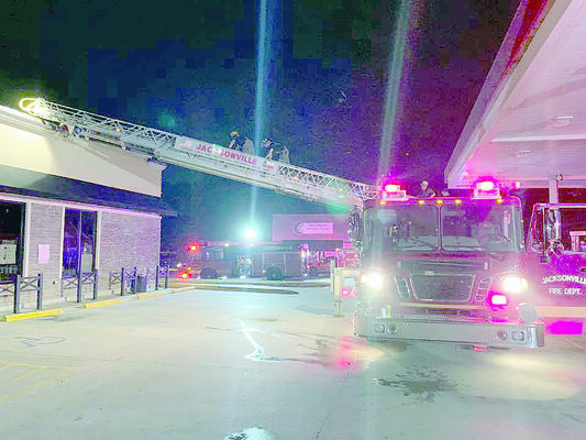 Courtesy photo
Jacksonville firefighters use the department’s ladder truck to bridge the span to the roof of a Jacksonville convenience store which caught fire recently.