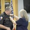 Phylena Hughes pins the chief’s badge to husband Stephen Hughes’ shirt, officially making him RPD’s new chief.